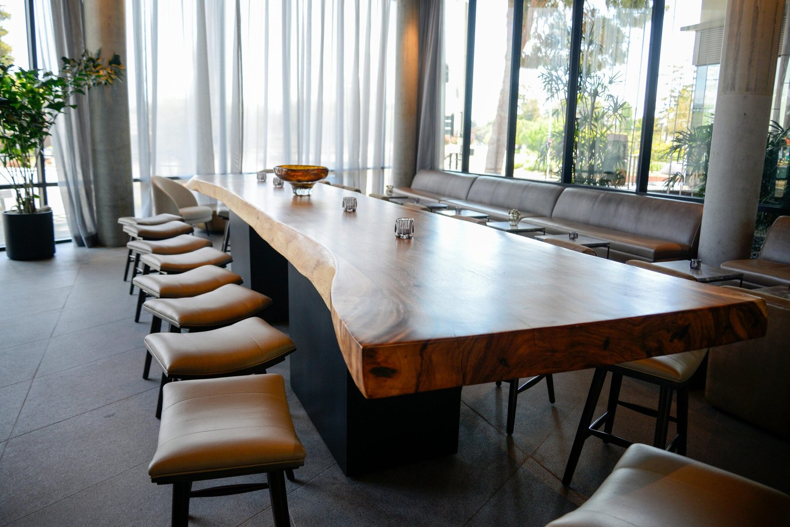 A stylish conference room featuring a long natural wood table, surrounded by chairs and large windows.