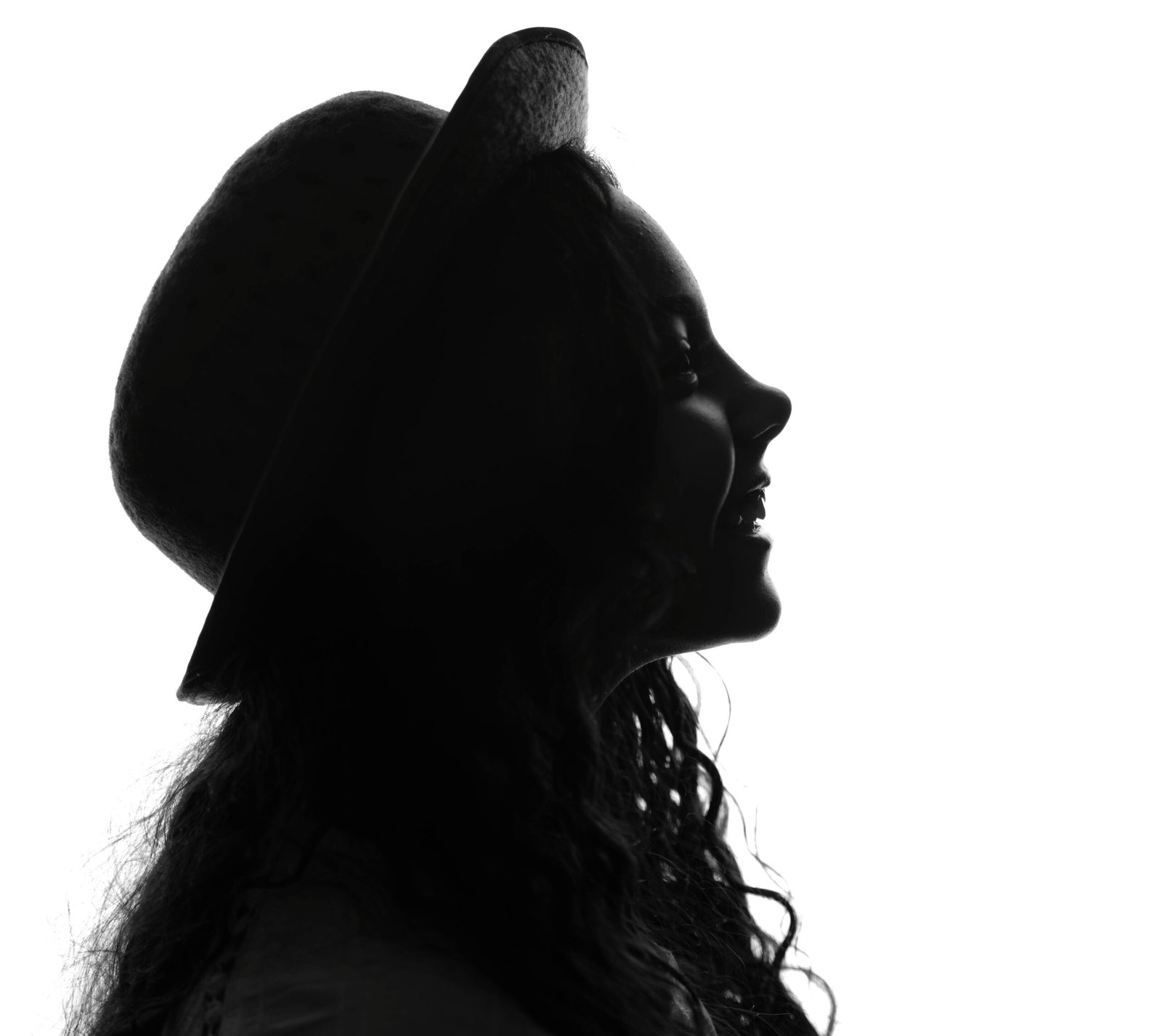 Artistic silhouette of a woman in profile wearing a hat, conveying elegance.